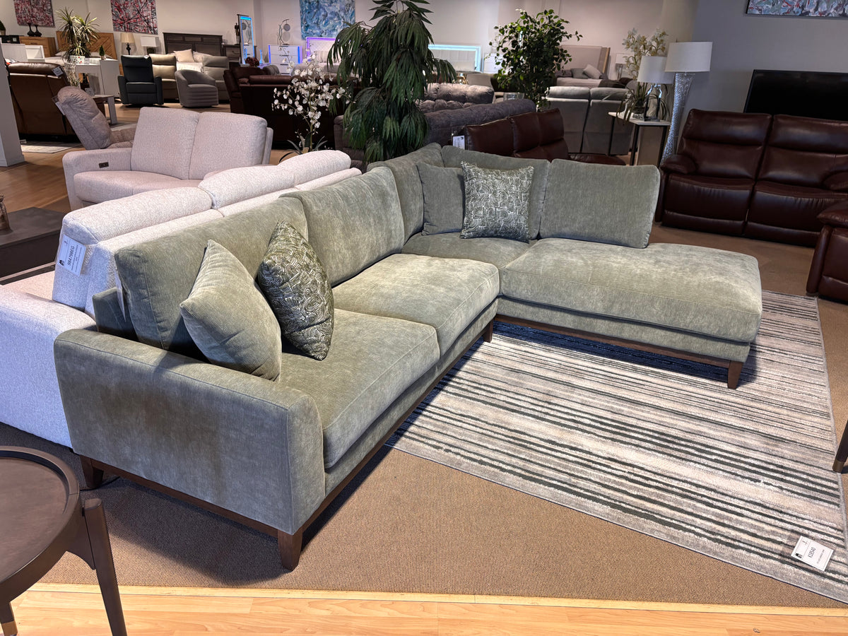 Model 8312GRN green upholstered sectional with right-facing chaise and accent cushions in showroom